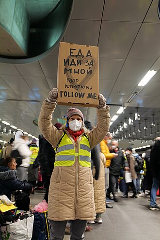 Person holds high a cardboard sign reading „food donations, follow me“