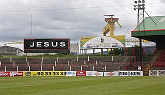 Black billboard next to stadium, with „JESUS“ in white letters