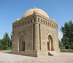 A cuboid building with a dome, in a greenery-enclosed plaza.