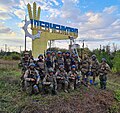 Ukraina hududiy mudofaa kuchlari askarlari Xarkov qarshi hujumidan keyin ozod qilingan Shevchenkovedagi yangi bo'yalgan (Rossiya bayrog'i ranglaridan Ukrainaga) kirish belgisi yaqinida.
