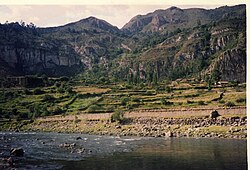 Photograph of a river and its riverbank with mountains in the background