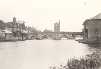 Photograph of a bridge over a river, with a rectangular building in the centre