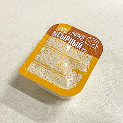 Moskvadagi McDonaldʻs restoranida Heinz pishloqli sousi paketchasi. Rossiya