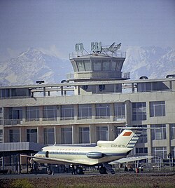 Togʻlar va aeroport binosi fonidagi Yak-40 samolyoti, 1974-yil.